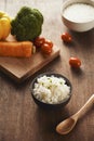Grains of rice in a wooden bowl and ingredients for a vegetarian recipe - healthy eating concept Royalty Free Stock Photo