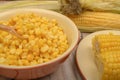 Grains of sweet corn in a plate and ears of corn on the wood table. Healthy diet. Fitness diet. For a sweet treat. Close up Royalty Free Stock Photo