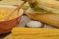 Grains of sweet corn in a plate with a wooden spoon, coarse salt and ears of corn on the table. Healthy diet. Fitness diet. For a Royalty Free Stock Photo