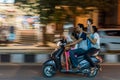 Grainy motion blur shot of a family of four riding on a scooter without wearing helmet dangerously