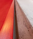 Grainy red lacquered wood and raw cement surface close up