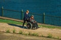 Woman pushing an elderly in wheelchair near a Lake