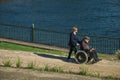 Woman pushing an elderly in wheelchair near a Lake
