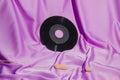 Gramophone vinyl record on purple silk curtain. Vintage composition. Royalty Free Stock Photo