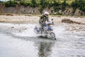 Gramsh, Albania - July 30, 2019. Moto biker crossing the river with splashing water Royalty Free Stock Photo
