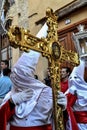 Penitent dressed in white and red from the Aurora de Granada procession looking back and holding his hood with a golden cross