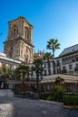 Outdoor restaurant in the center of Romanilla Plaza with bell tower of Granada Cathedral at background. Spain Royalty Free Stock Photo