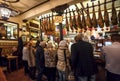 People drinking and eating at traditional tapas bar with dry-cured ham legs and vintage decor