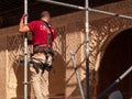 Man working on the restoration of the Alhambra. Renovation of the historical site in Granada. Scaffold and harness