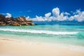 Grand Anse beach at La Digue island in Seychelles. Rolling wave at sandy beach with blue ocean lagoon. White clouds in