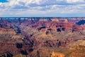 Grand canyon from South rim viewpoint. Brlliant colors of the northern wall; clouds overhead. Royalty Free Stock Photo