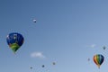 Blue sky and clouds, with several colourful hot-air balloons