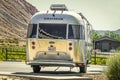 Airstream camper trailer parked on concrete with grape vineyards and mesa and barn behind