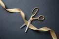 Grand opening. Gold scissors cutting gold satin ribbon, black background Royalty Free Stock Photo