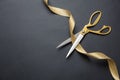 Grand opening. Gold scissors cutting gold satin ribbon, black background Royalty Free Stock Photo