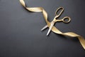 Grand opening. Gold scissors cutting gold satin ribbon, black background Royalty Free Stock Photo