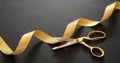 Grand opening. Gold scissors cutting gold satin ribbon, black background Royalty Free Stock Photo