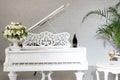 Grand piano in a luxury white classic interior with wine, palms and flowers. Royalty Free Stock Photo