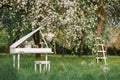 Grand piano and white staircase with romantic decor in spring in a blossoming Apple tree garden