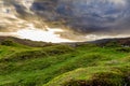 Grand swirling clouds before sunset over rolling green grass cut short by sheep near the Royal Castle of Tarbert in Argyll and