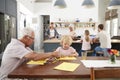 Grandad and grandson drawing together in busy family kitchen