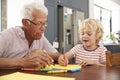 Grandad and grandson drawing together in family kitchen, close u