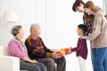 Grandchild with parents giving a gift to grandparents