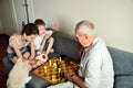 Grandchildren with grandpa playing chess