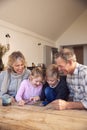 Grandchildren With Grandparents Playing On Digital Tablet At Home Together Royalty Free Stock Photo