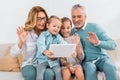 grandchildren and grandparents waving by hands while having video call with digital tablet