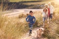 Grandchildren And Pet Dog Exploring Sand Dunes With Grandparents On Winter Beach Vacation Royalty Free Stock Photo