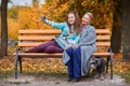 Granddaughter makes selfie with grandmother with a slight smile in the autumn park