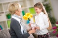 Granddaughter bringing yellow flowers to her grandmother Royalty Free Stock Photo