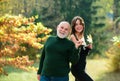 Granddaughter with elderly grandfather standing outdoors in autumn park. Caring adult daughter spend time with old dad. Royalty Free Stock Photo
