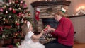 Granddaughter gives grandmother a Christmas present and kisses and hugs her by the tree Royalty Free Stock Photo