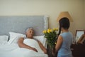 Granddaughter giving flowers to grandmother in bed room Royalty Free Stock Photo