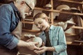 Granddaughter and grandfather holding and examining clay goods