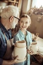 Granddaughter and grandfather holding and examining clay goods