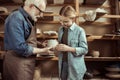 Granddaughter and grandfather holding and examining clay goods