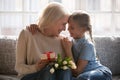 Granddaughter grandmother cuddling celebrating granny birthday with flowers and gift