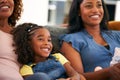 Granddaughter With Grandmother And Mother Relaxing At Home Sitting On Sofa Watching TV Together Royalty Free Stock Photo