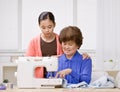 Granddaughter and grandmother use sewing machine