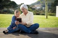 Granddaughter and grandmother using a digital tablet in the deck shade Royalty Free Stock Photo