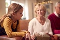 Granddaughter With Grandparents Opening Gifts Around Christmas Tree At Home Royalty Free Stock Photo