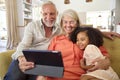 Granddaughter And Grandparents On Sofa At Home Making Video Call On Digital Tablet Royalty Free Stock Photo