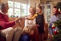 Granddaughter Handing Out Presents To Multi-Generation Family Around Christmas Tree At Home Royalty Free Stock Photo