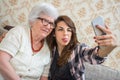 Granddaughter and her grandmother taking selfie with smart phone at home. Royalty Free Stock Photo