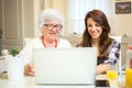 Granddaughter and her grandmother using laptop together at home. Royalty Free Stock Photo