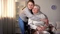 Granddaughter hugging smiling old woman in wheelchair, family love and care