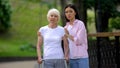 Granddaughter hugging upset old grandma with walker looking at camera outdoors Royalty Free Stock Photo